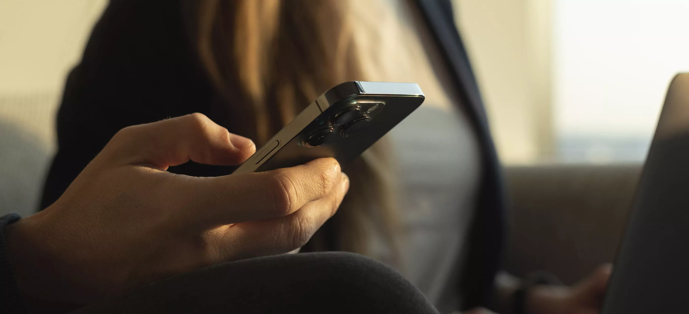 Person using a smartphone and laptop simultaneously, representing mobile and web app development solutions for seamless digital experiences.